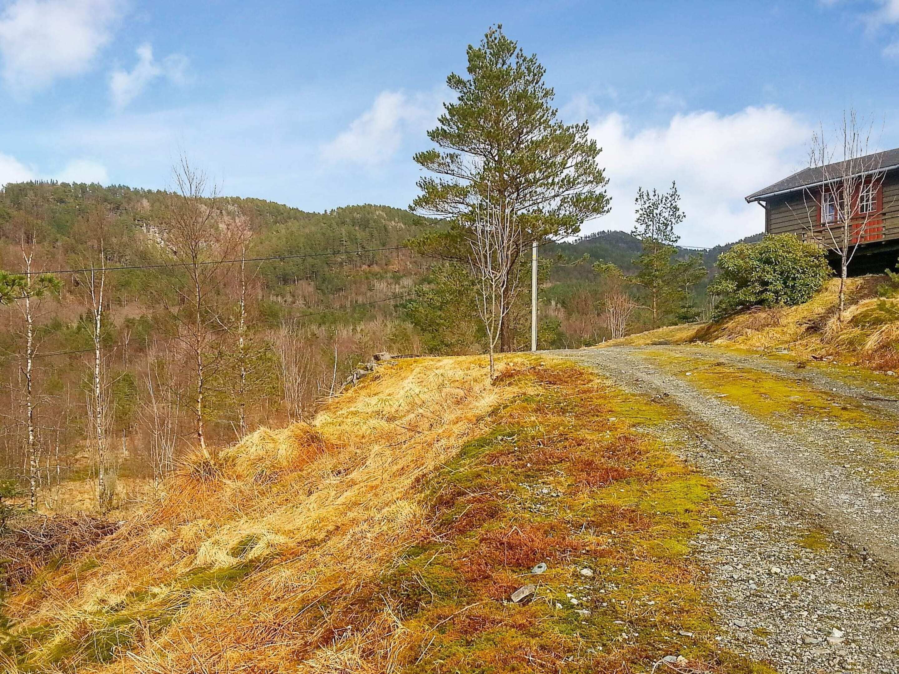 A gravel path leading to a building with a sloped roof and red trim.
