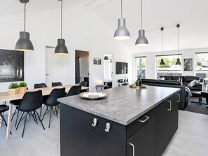 A modern kitchen with a central island, black cabinetry, and pendant lighting.