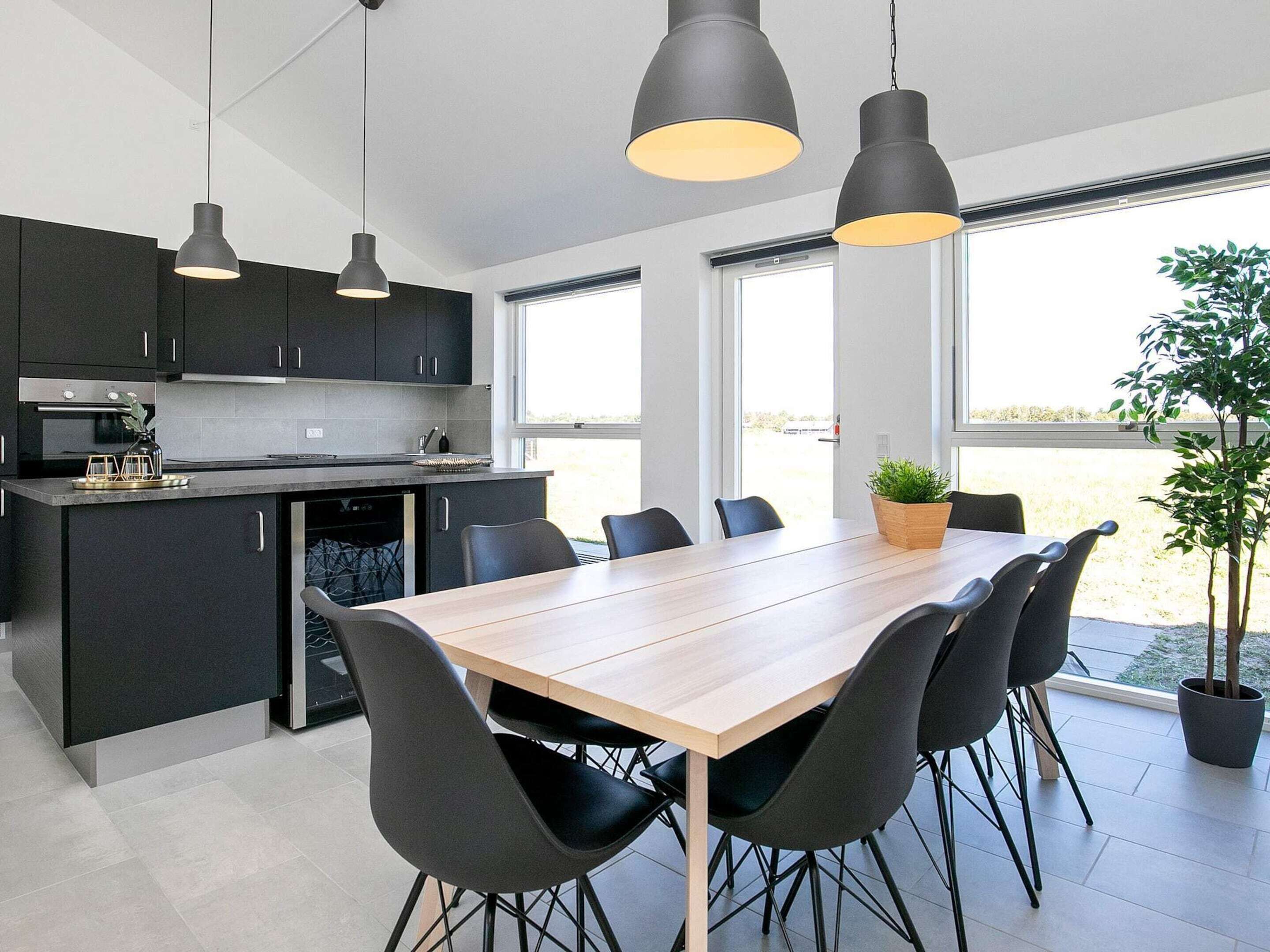A modern kitchen with dark cabinetry, a central island, and pendant lighting.