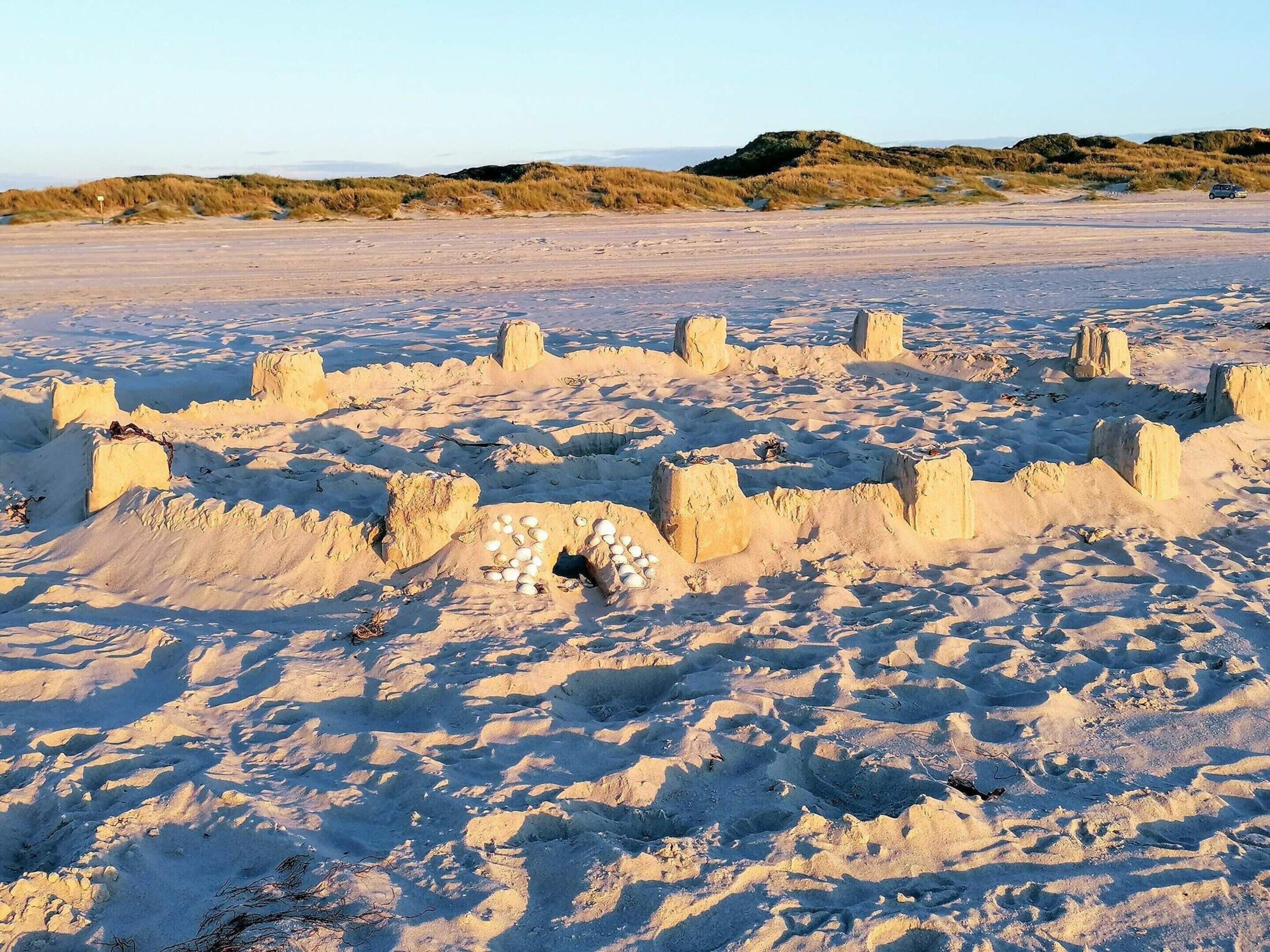A sandy landscape with large sand formations and dunes in the background.