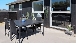 Un espace patio aménagé avec une table et des chaises, une plante en pot et un petit objet décoratif.