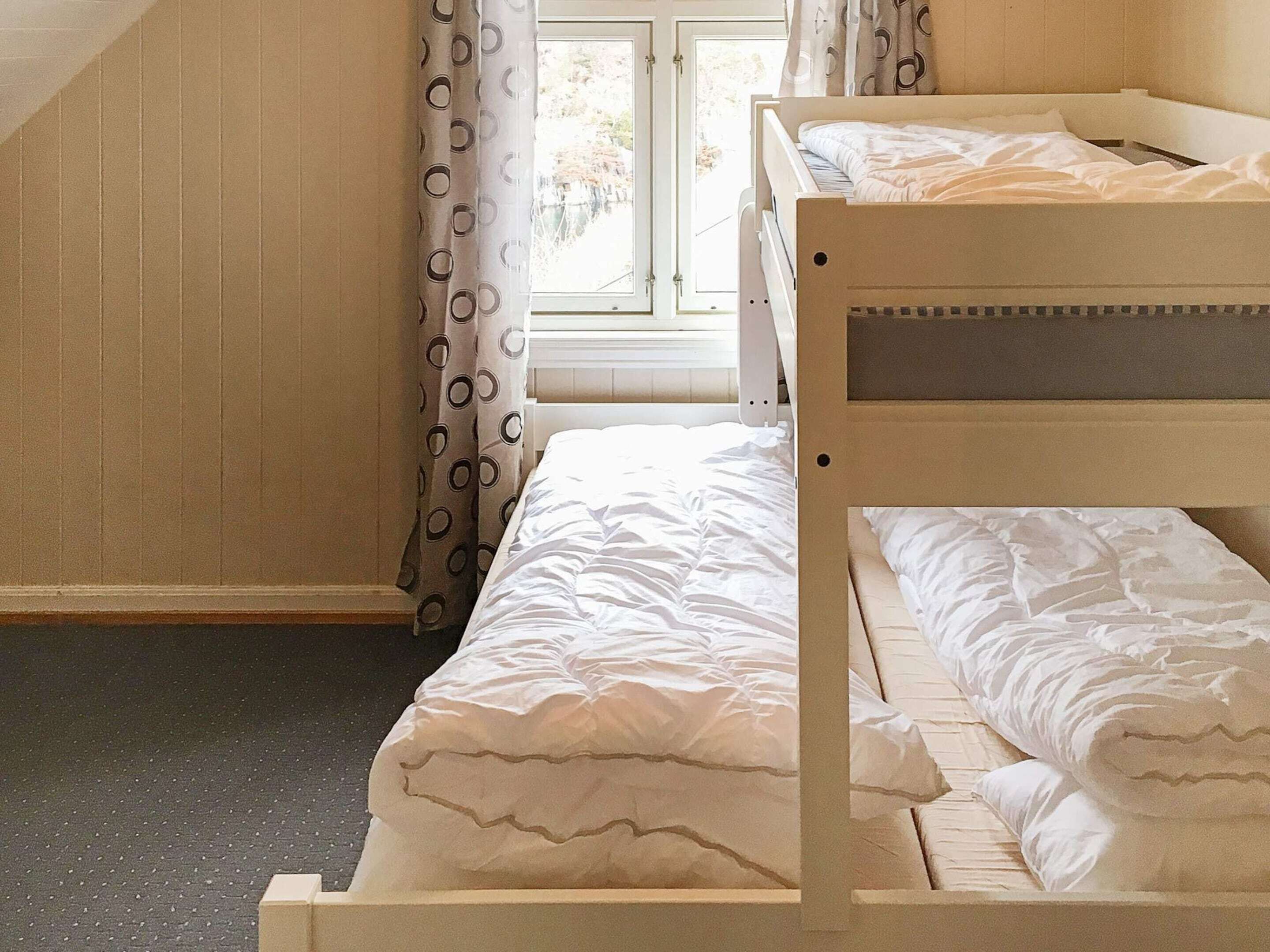 Dormitorio con literas, ventana, cortinas y piso alfombrado.