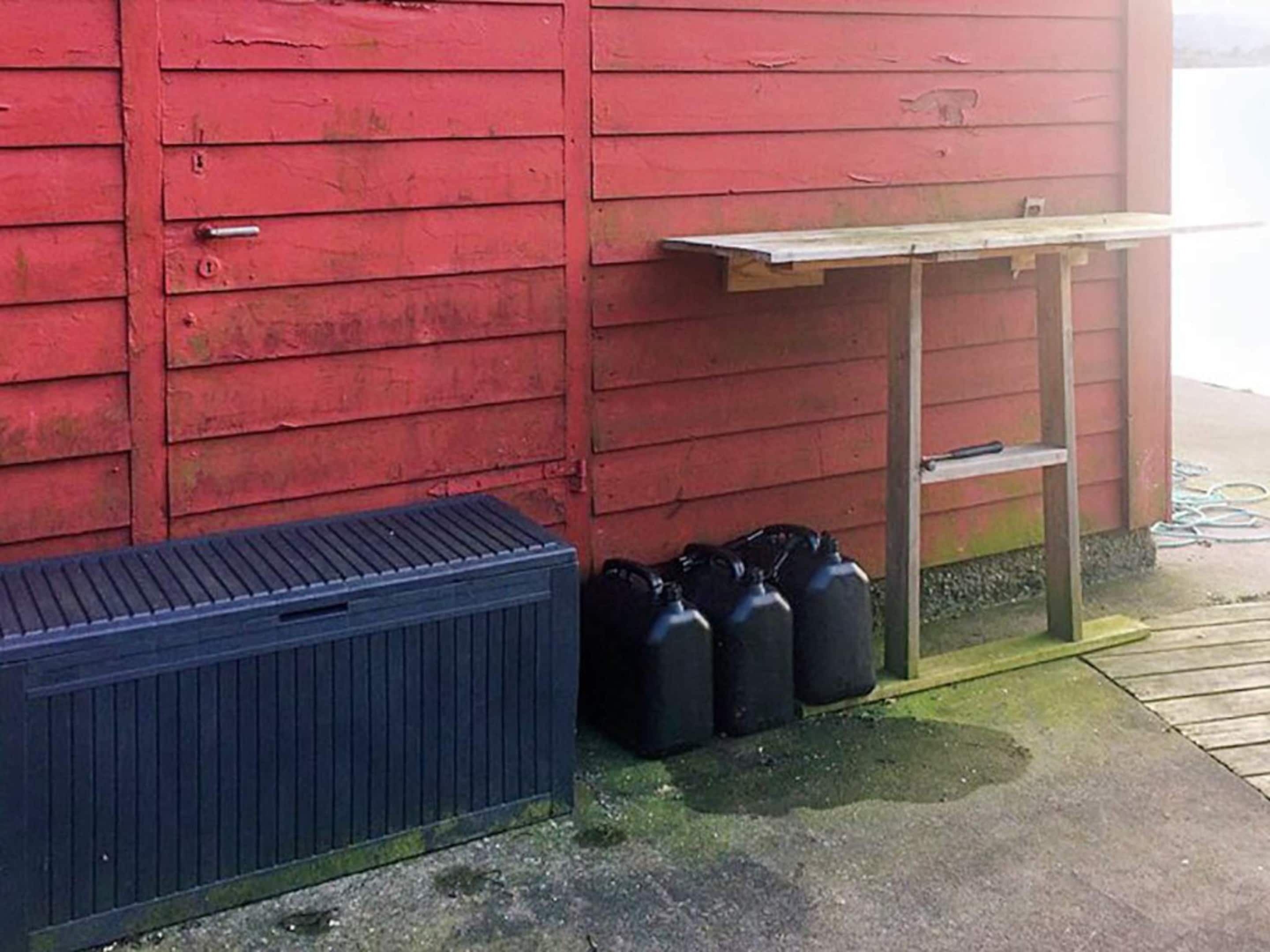 A red building with a black container and black gas cylinders against it.