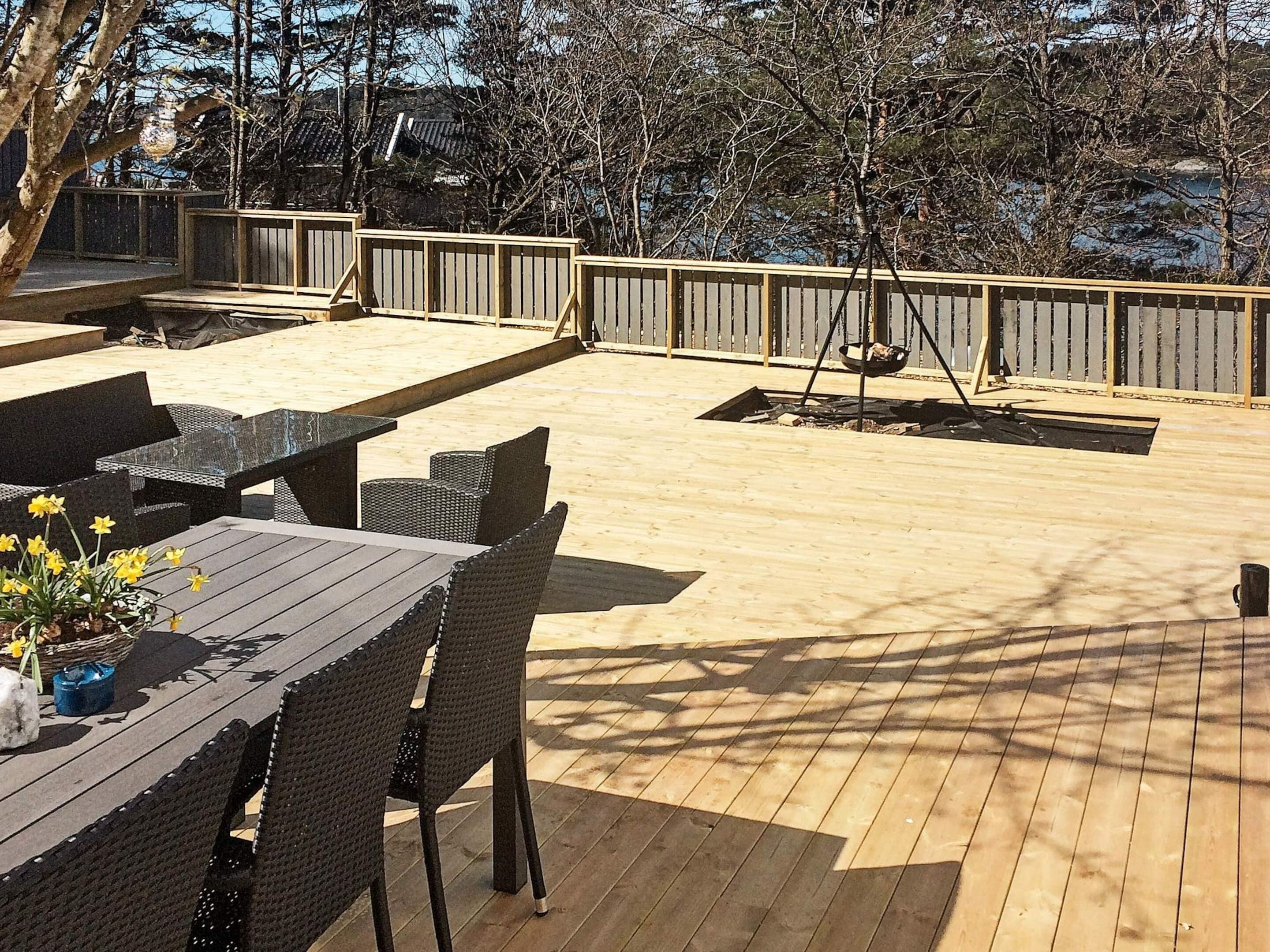 A wooden deck with outdoor furniture, including a table and chairs, and a swing set.