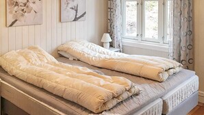 Ein Schlafzimmer mit zwei Einzelbetten, einem Fenster mit Vorhängen und Wandbildern.
