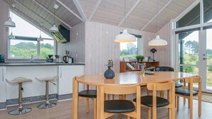 Una cocina moderna con una mesa y sillas de madera, horno empotrado y un amplio ventanal con vistas a zonas verdes.