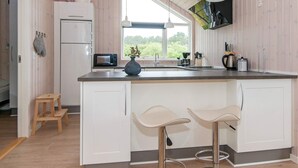 Una cocina moderna con armarios blancos, un microondas integrado, un fregadero y dos taburetes de bar.