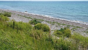 Un paisaje costero con playa de guijarros y zonas de hierba.