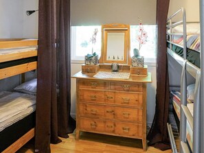 A dormitory room with a wooden dresser, a mirror, and a window with curtains. - 8 Person Holiday Home in Hyltebruk (Hyltebruk)