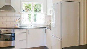 A modern kitchen with white cabinets, a stainless steel oven, a refrigerator, and a window with plants. - 8 Person Holiday Home in Hyltebruk (Hyltebruk)