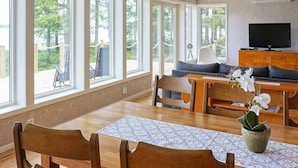 A dining area with a wooden table, chairs, and a bench. There is a television on a wooden cabinet, and a potted plant on the table. - 8 Person Holiday Home in Hyltebruk (Hyltebruk)