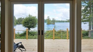 A wooden deck with a view of a lake and trees. - 8 Person Holiday Home in Hyltebruk (Hyltebruk)