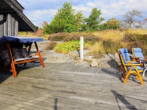 A wooden deck with a swing chair and two lounge chairs. - Holiday Home in Henån (Henån)