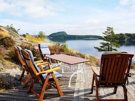 Una terraza de madera con mesa y sillas con vistas a un lago.
