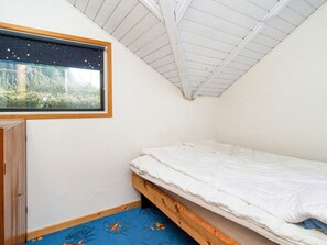 A small, single-bed room with a sloped ceiling and a window with a starry night view. - 6 Person Holiday Home in Skibby (Skibby)