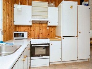 A compact kitchen with a microwave, stove, oven, and white cabinets. - 6 Person Holiday Home in Skibby (Skibby)