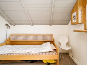 A single bed with a wooden frame and a checkered headboard, a white chair, and a small wooden shelf with a poster. - 6 Person Holiday Home in Skibby (Skibby)