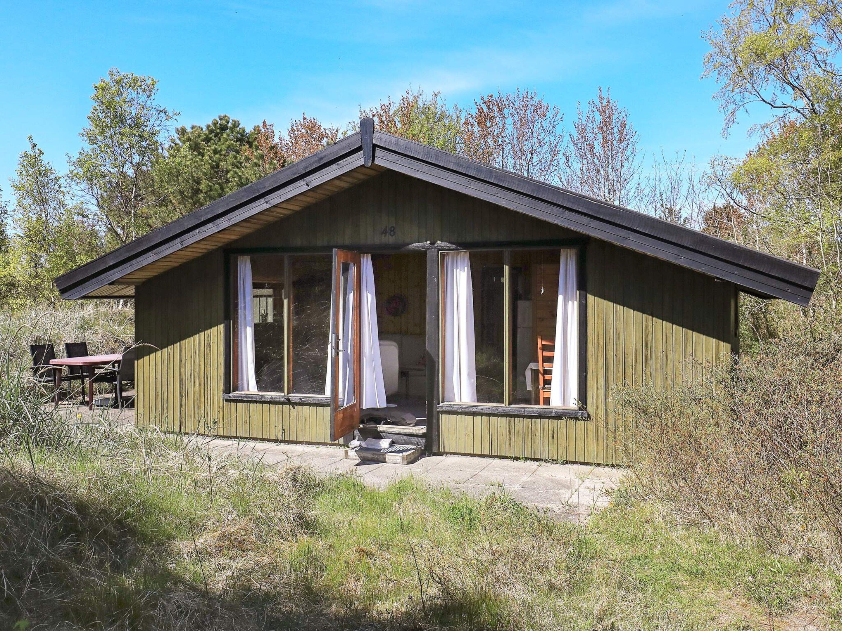 A wooden cabin with a pitched roof, large windows, and a visible door.