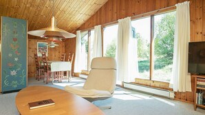 A wooden interior with a dining area, a large window, and a television. - Vintage Holiday Home in Jutland near Child Friendly Beach (Aalbaek)