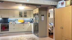 A modern kitchen with light wood cabinets, stainless steel appliances, and a black and white rug. - 4 Person Holiday Home in Ormaryd (Ormaryd)