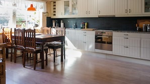 A kitchen with wooden cabinets, a dining table with chairs, and a window with curtains. - 4 Person Holiday Home in Ormaryd (Ormaryd)