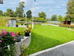 A well-maintained lawn with a stone wall, potted plants, and a small shed. - 4 Person Holiday Home in Ormaryd (Ormaryd)