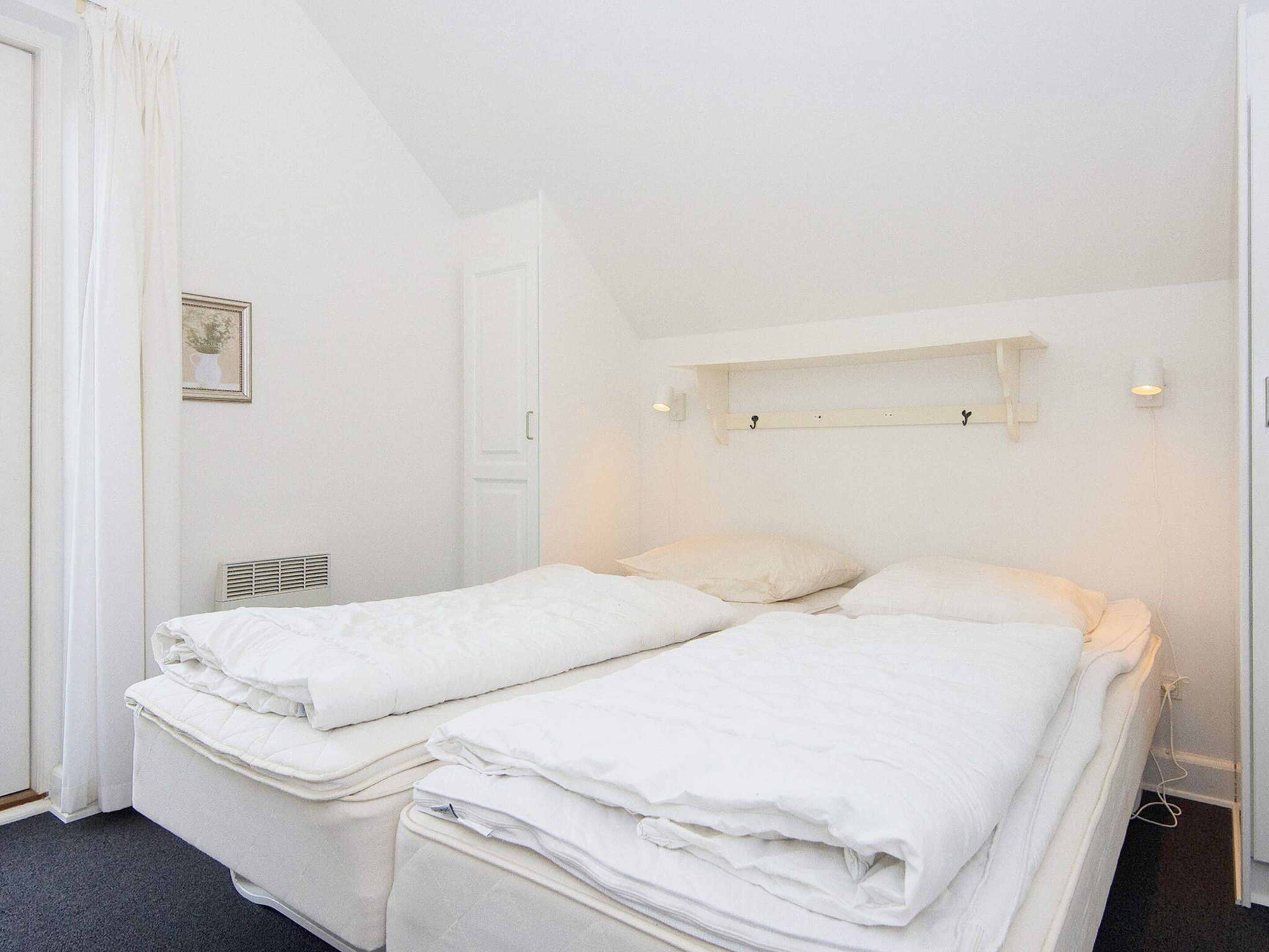 A twin bed room with a white headboard, a bedside table, and a wall-mounted shelf.