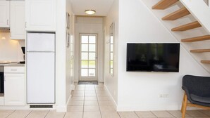 A modern kitchen with white cabinets, a built-in refrigerator, and a flat-screen TV mounted on the wall. - 4 Star Holiday Home in Gjern (Gjern)