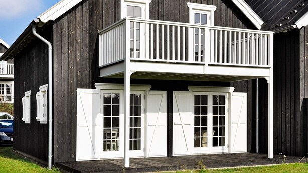 A two-story wooden building with a balcony and white-framed windows. - 4 Star Holiday Home in Gjern (Gjern)