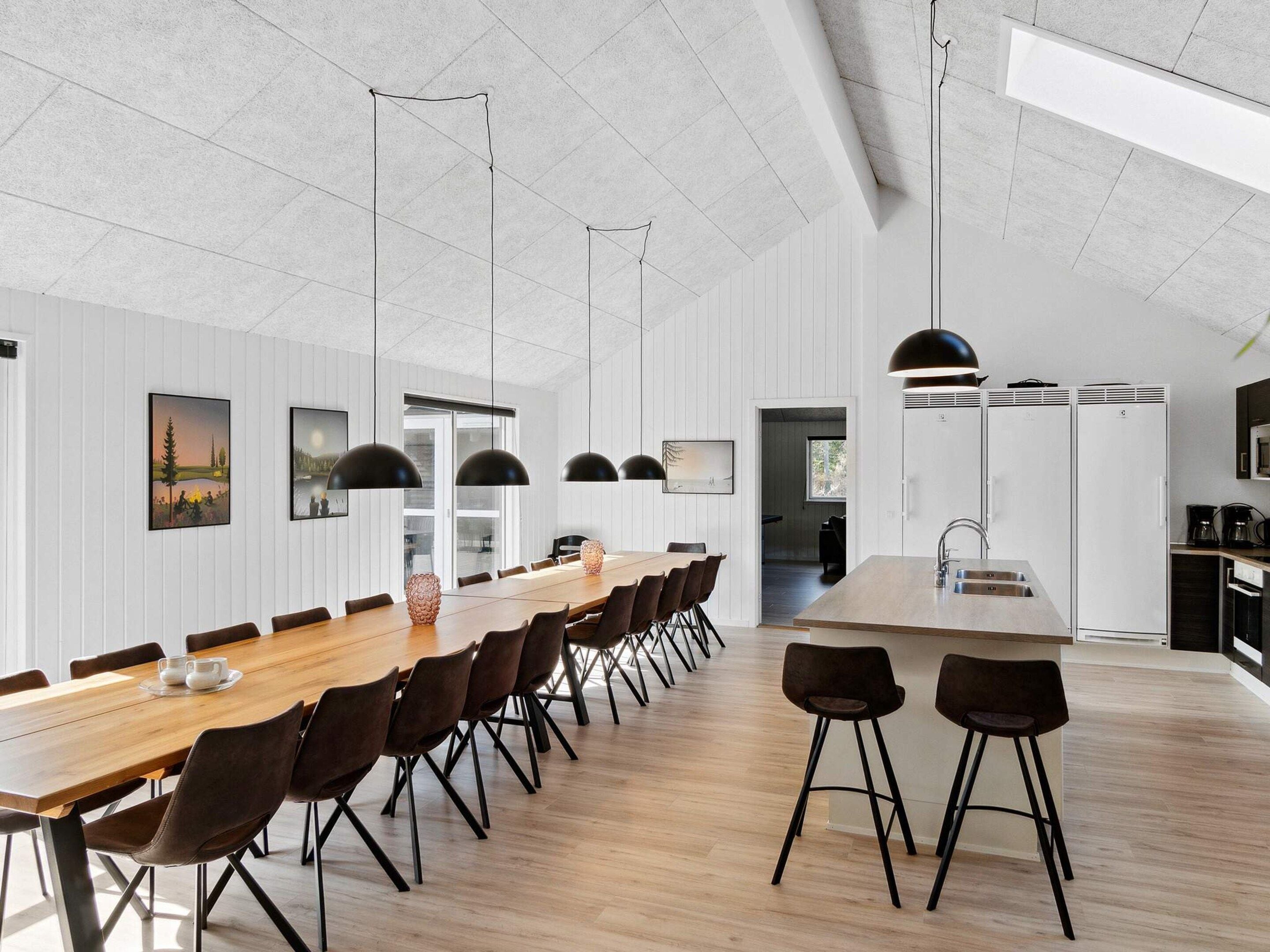 A modern kitchen with a central island, pendant lighting, and a view into the dining area.