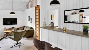 Uma sala de estar moderna com uma escada de madeira, uma área de jantar com uma mesa redonda e um espaço de bar com um espelho.