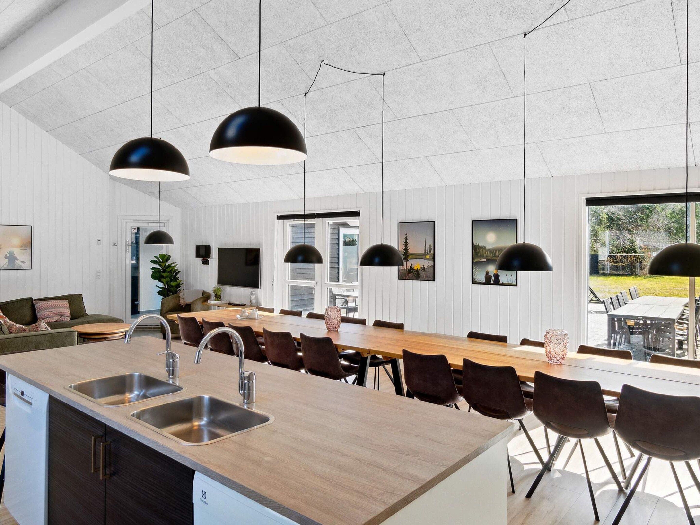 Una cocina moderna con una isla central, electrodomésticos integrados e iluminación colgante.