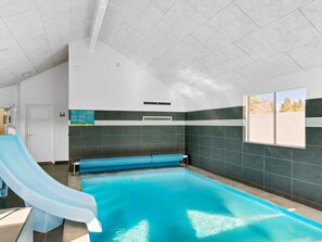 A swimming pool with a slide, a window with a view, and a door.