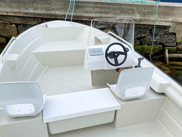A boat with a Garmin steering wheel, a clear windshield, and a white interior. - 9 Person Holiday Home in Reksteren (Tysnes)