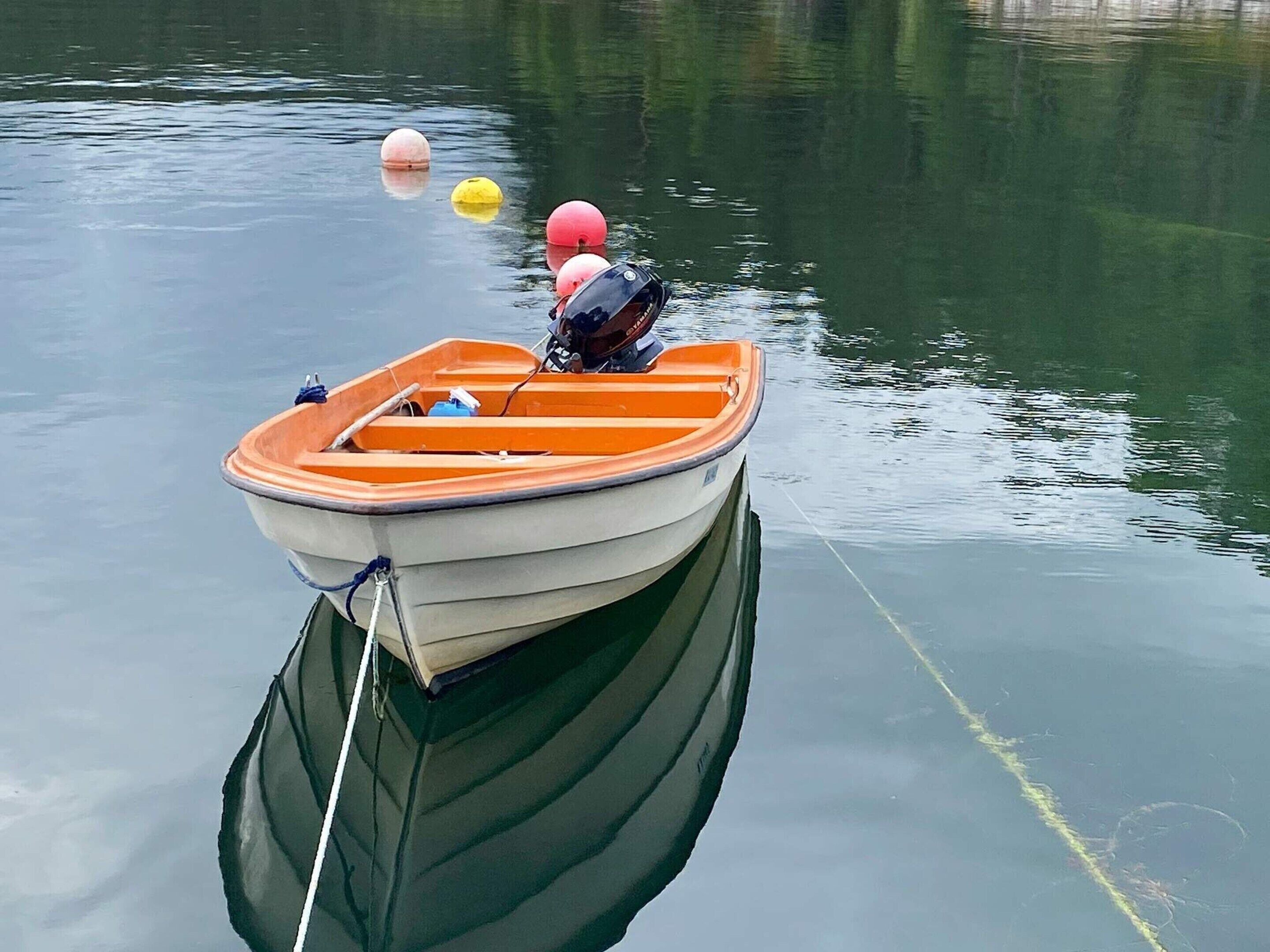 A small boat with an outboard motor anchored in calm water.