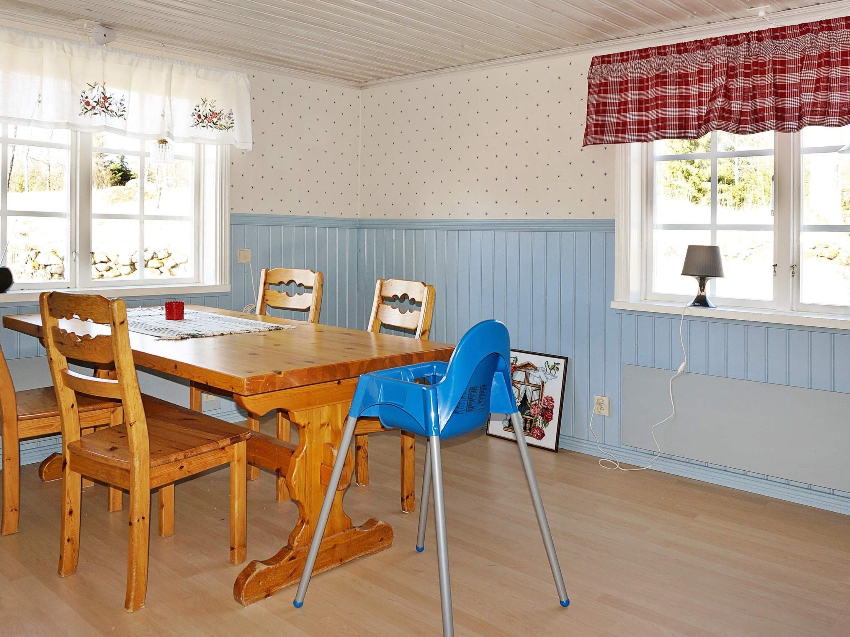 En matplats med ett träbord, fyra stolar och en blå, hopfällbar stol.