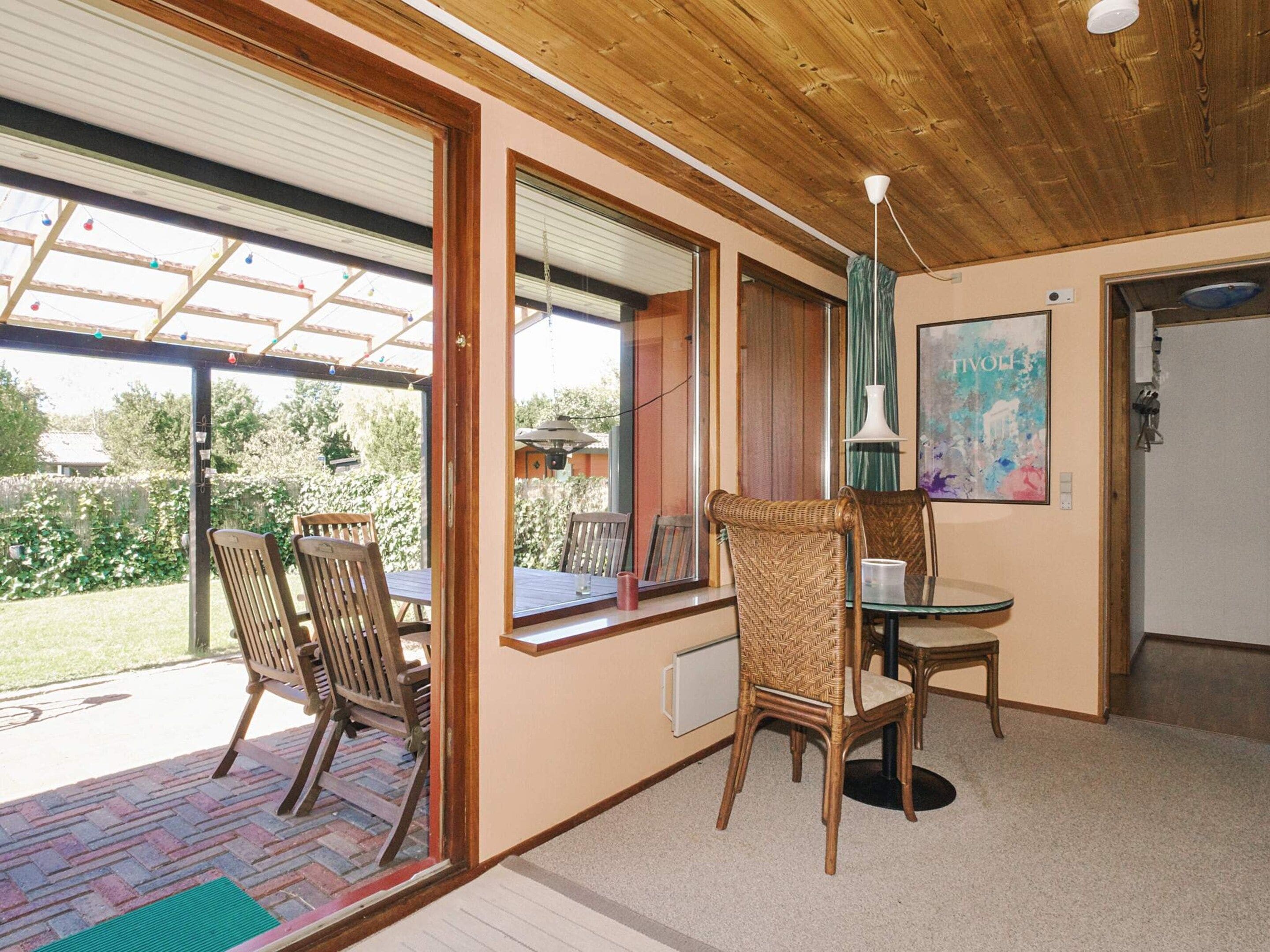 A room with a dining table and chairs, a window with a view of the outdoors, and a ceiling fan.