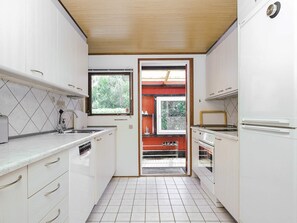 A compact kitchen with white cabinets, a built-in oven, and a window providing natural light.