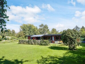 A house with a solar panel roof, surrounded by a well-maintained lawn and dense trees. - 6 Person Holiday Home in Store Fuglede (Store Fuglede)