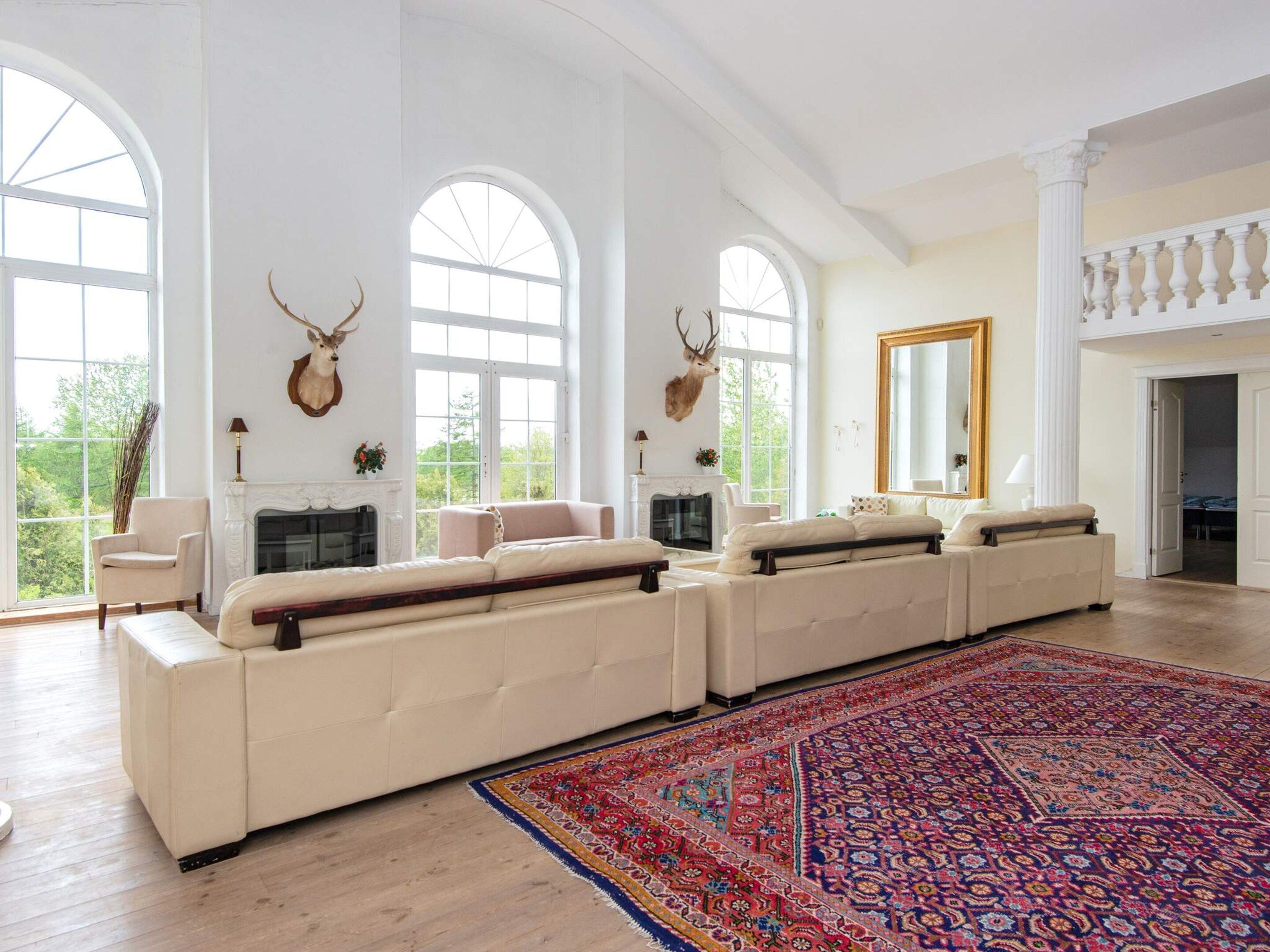 Un salón espacioso con un amplio sofá modular, una chimenea y un ventanal grande.