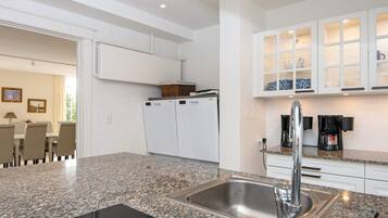 Cocina moderna con encimeras de granito, pileta de acero inoxidable y muebles blancos.