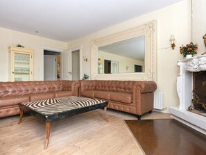 A living room with a brown leather sofa, a zebra-patterned coffee table, a large mirror, and a fireplace with decorative elements.