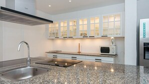 A modern kitchen with granite countertops, white cabinets, and built-in appliances. - 5 Star Holiday Home in Lunderskov (Lunderskov)