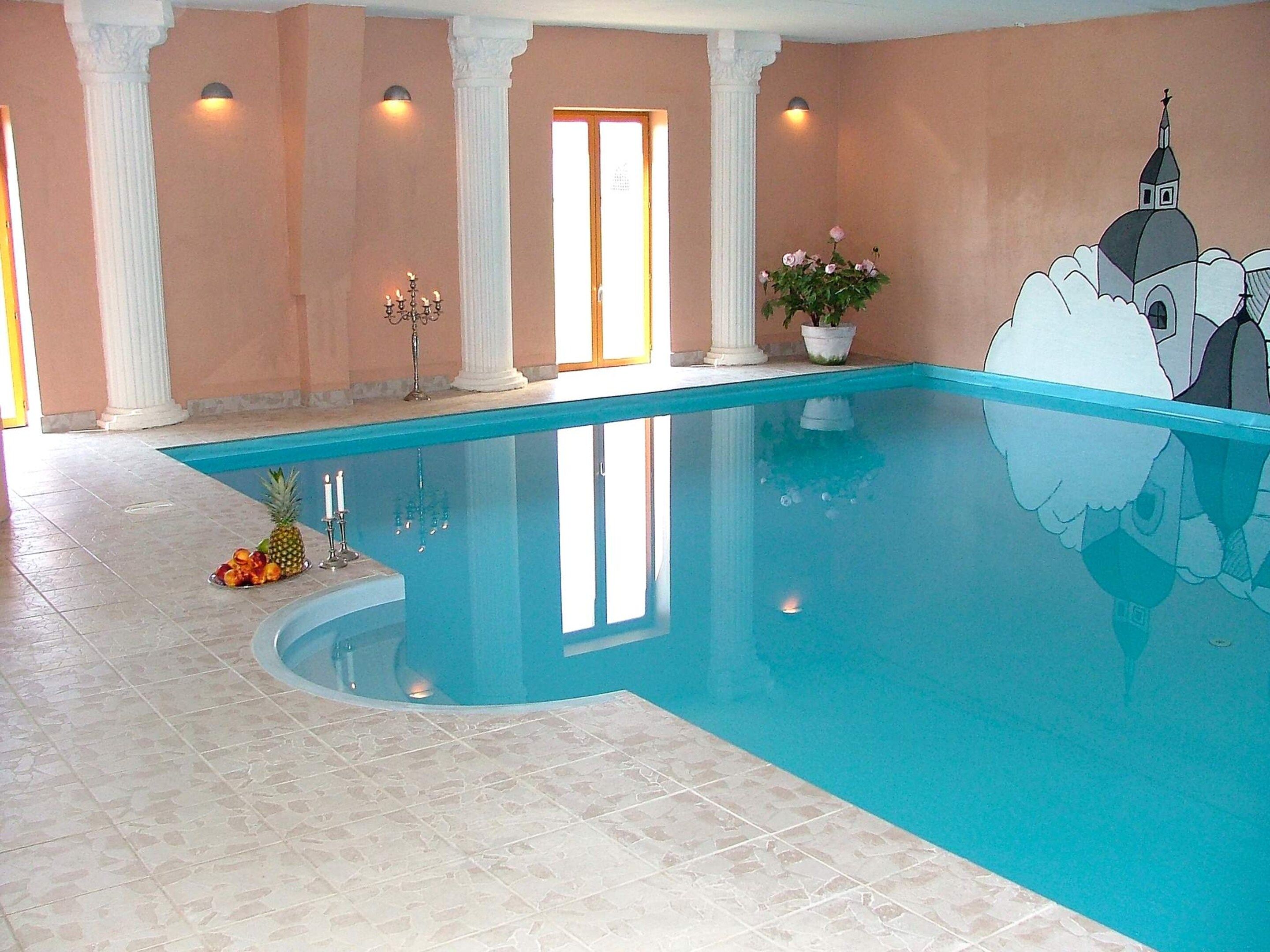 Una piscina interior con suelo de baldosas, una piña y una planta en maceta.