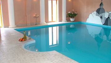 Una piscina interior con suelo de baldosas, una piña y una planta en maceta.