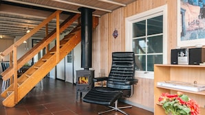 A room with a wooden staircase, a black leather chair, a fireplace, and a window with a view.