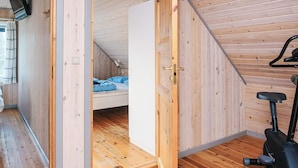 A wooden interior with a bed, exercise bike, and a door leading to another room.