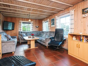 Una habitación acogedora con un sofá, una silla, una mesita y una televisión.