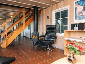 A room with a wooden staircase, a black leather chair, a fireplace, and a window.