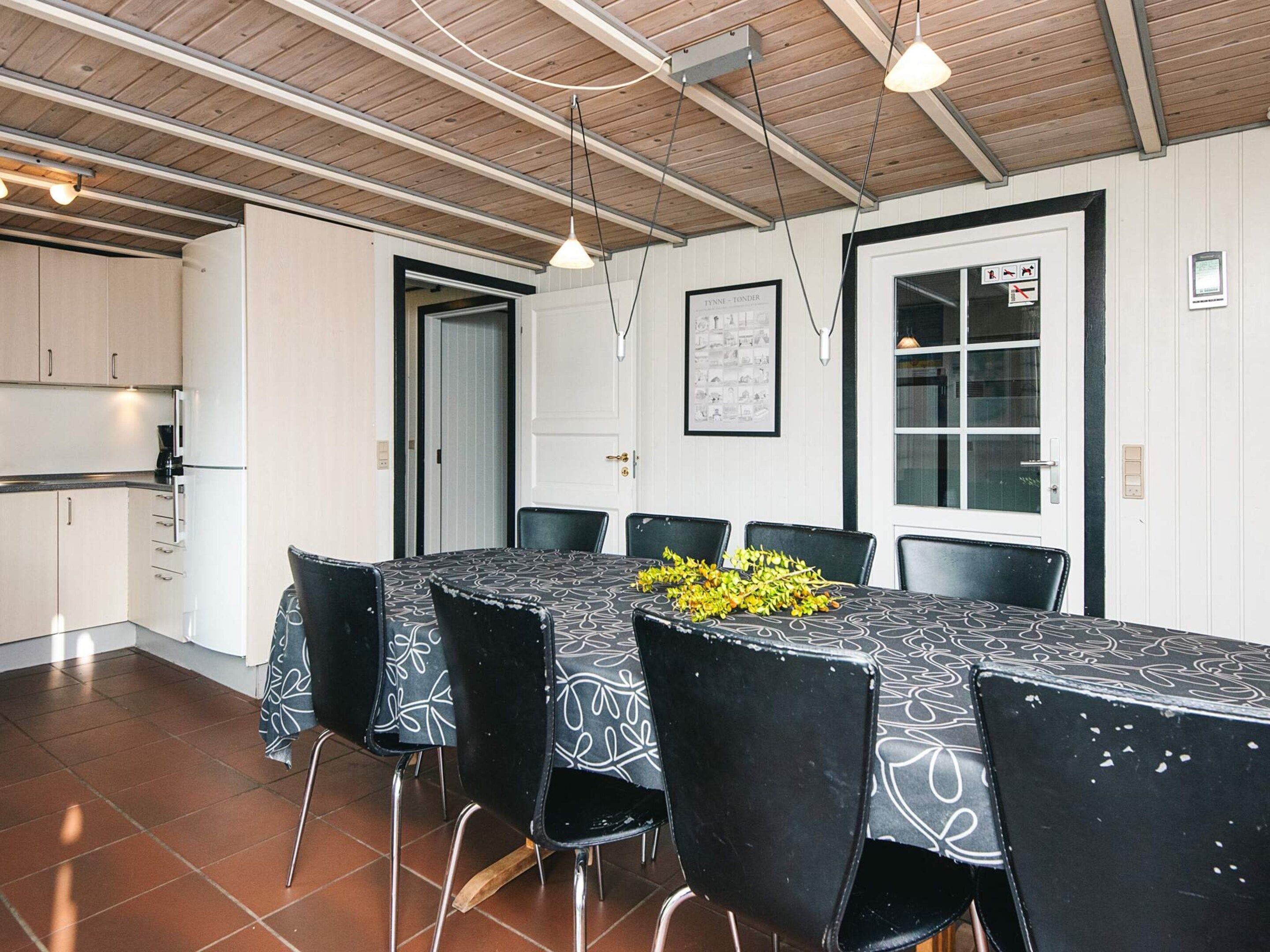A dining area with a table set for six, surrounded by black chairs with white patterns.
